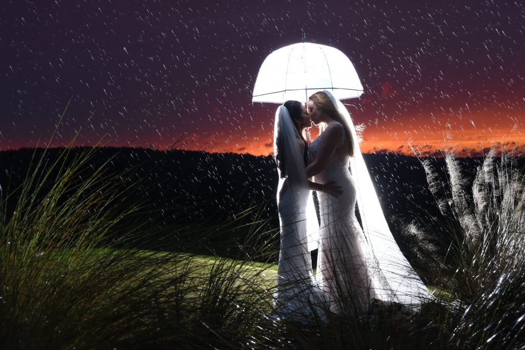 Brides Kissing Under Glowing Umbrella Sunset | Anna Christine Events Orlando Central Florida Wedding Planner