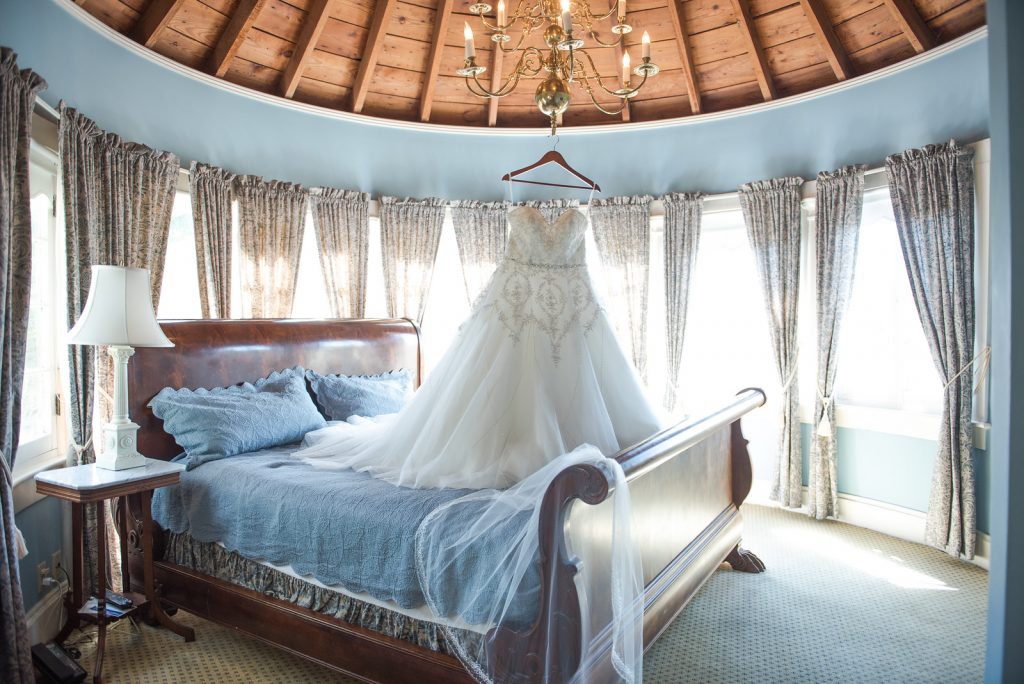 Wedding Dress Hanging from Chandelier on Bed | Classic Purple & Orange Wedding Football Texas Longhorns Sports Lake Lucerne Courtyard Anna Christine Events Orlando Kathy Thomas Photography