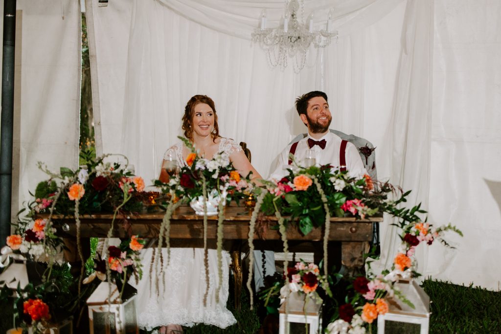 bride and groom sit at sweetheart table on wedding day planned by anna christine events in orlando wedding
